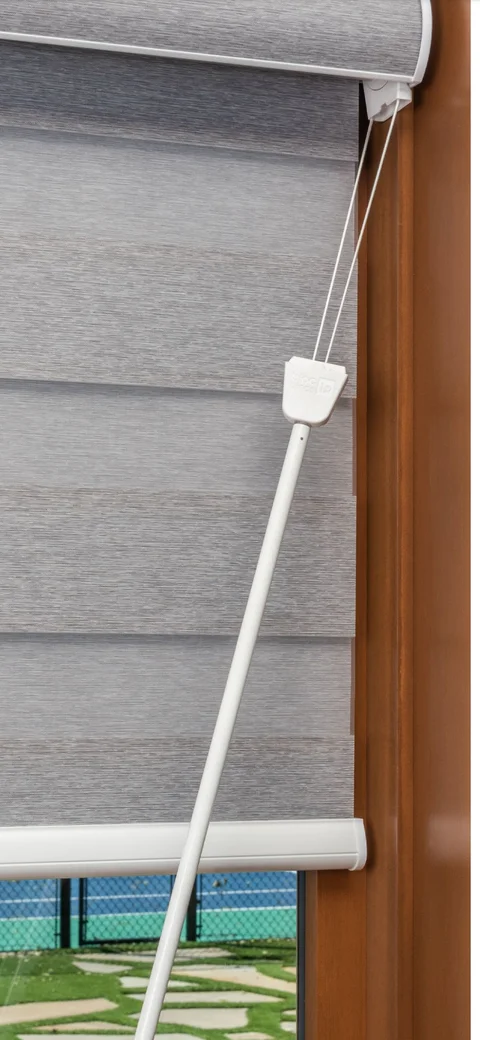 White Bloc twist wand attached to the control end of a grey roller blind.
